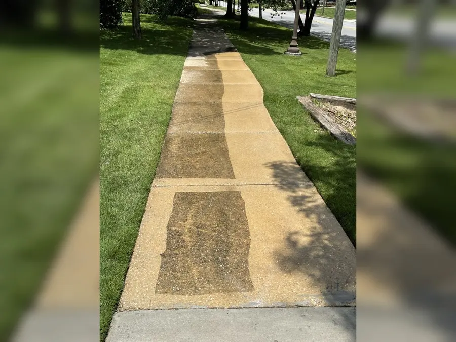 Concrete sidewalk partly pressure washed in stripes